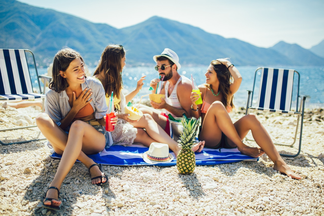 Summer bucket list activities - A group of friends enjoying fruity drinks by the beach.